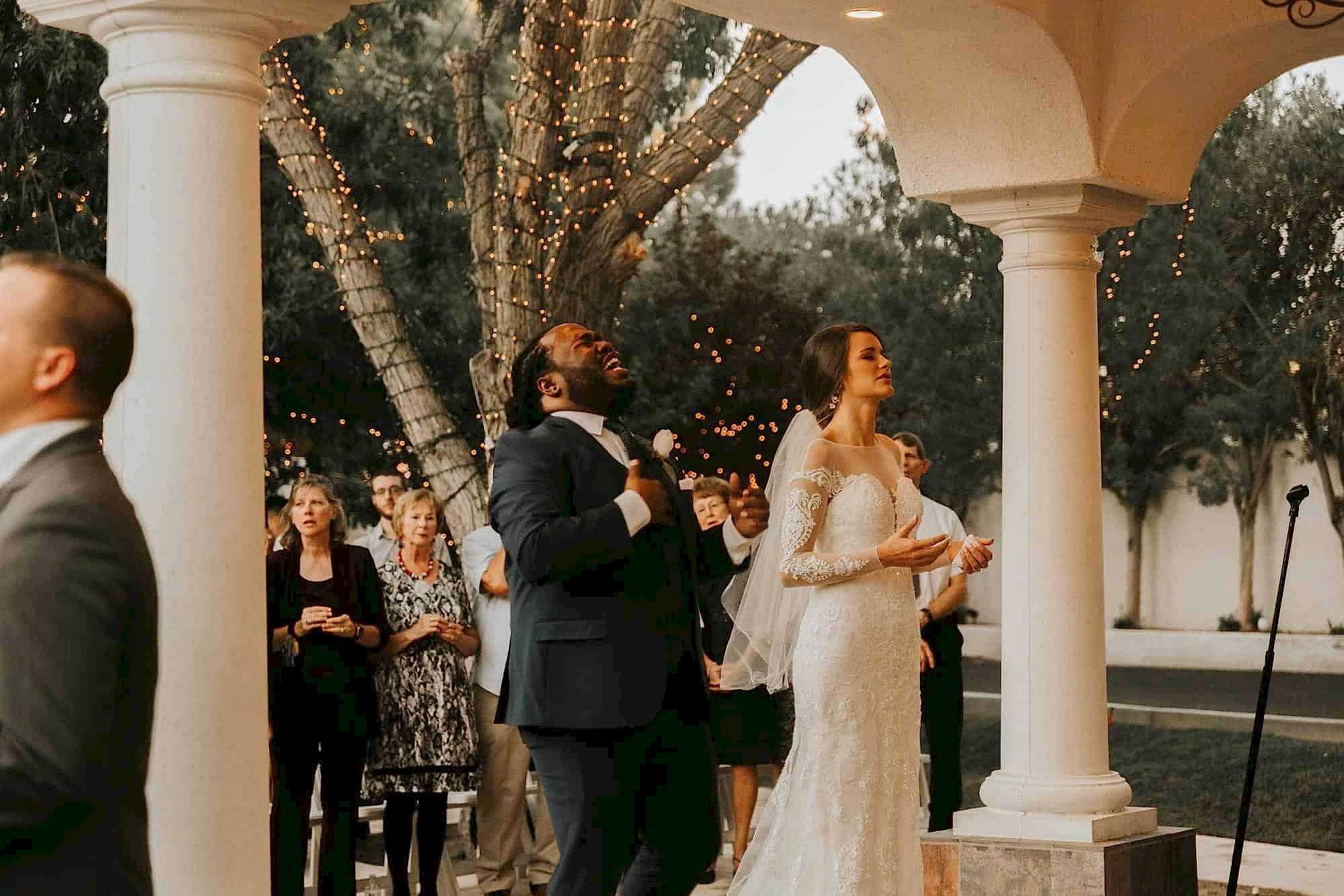 A bride and groom laugh during their unity ceremony on their wedding day at an outdoor wedding venue