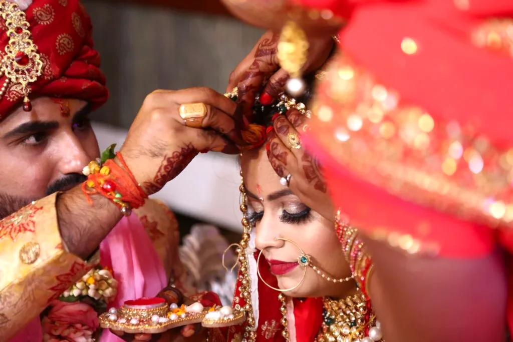 An Indian groom touches his bride’s forehead at their wedding ceremony