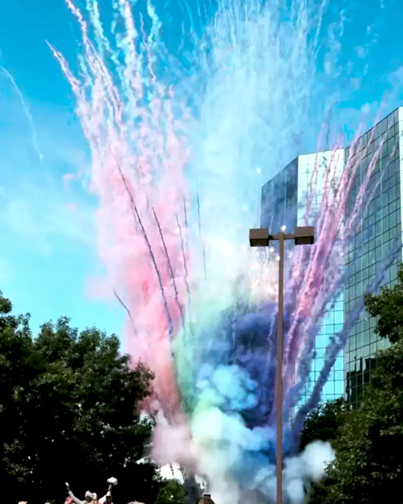 Smoke mines going off outdoors to reveal massive plumes of green, pink, blue, and purple smoke