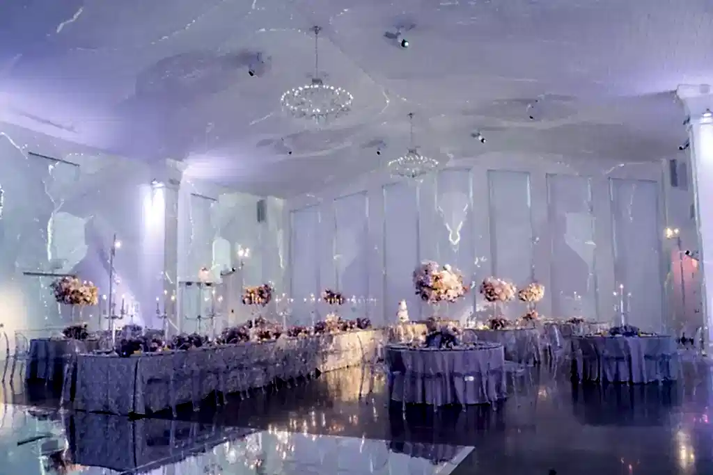 A unique wedding venue with a banquet table, surrounded by smaller tables. All decorated with candles and flowers.