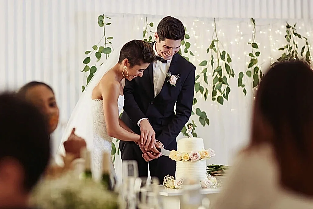 A couple cuts cake while they listen to a song from the best wedding songs playlist